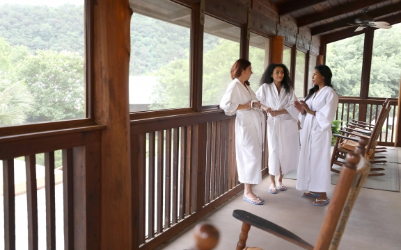 A group of three women in robes chatting outside the Blue Room