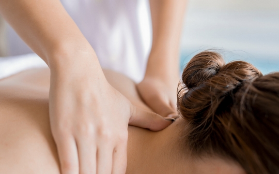 An up-close shot of a woman receiving a neck massage from a professional masseuse.